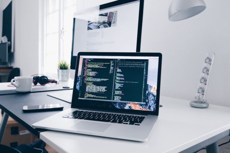 Portfolio Freelancer - A MacBook with lines of code on its screen on a busy desk