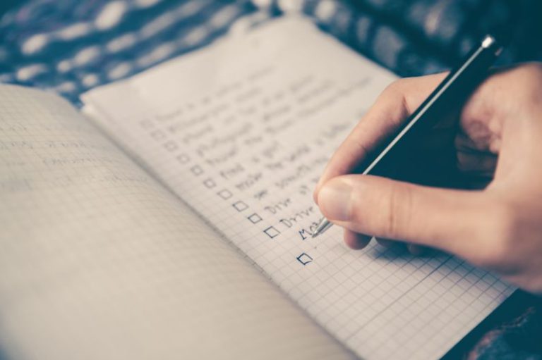 Time Management - person writing bucket list on book