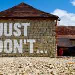 Saying No - brown brick building with red car parked on the side