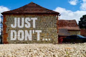 Saying No - brown brick building with red car parked on the side