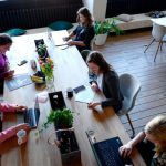 Women Leaders - a group of people sitting around a wooden table