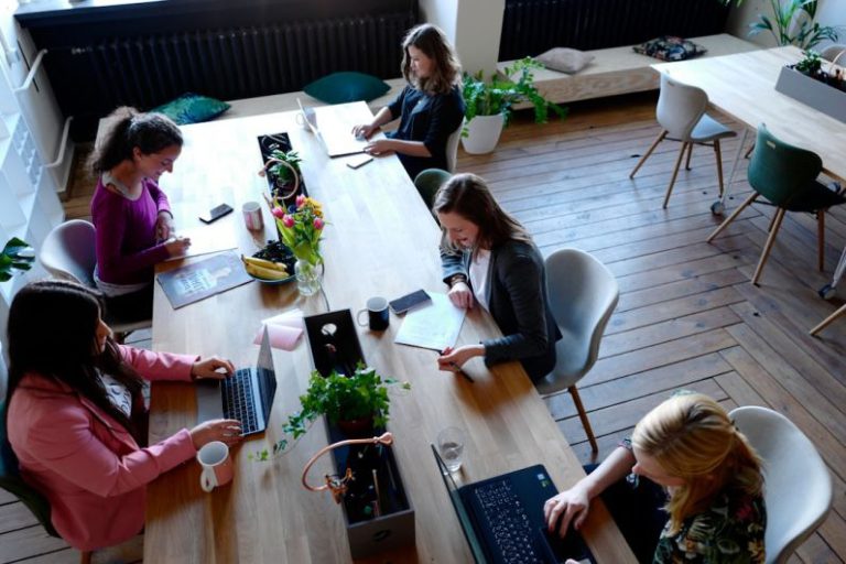 Women Leaders - a group of people sitting around a wooden table