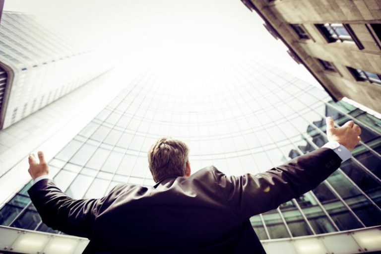 Failure Success - low-angle photography of man in the middle of buidligns