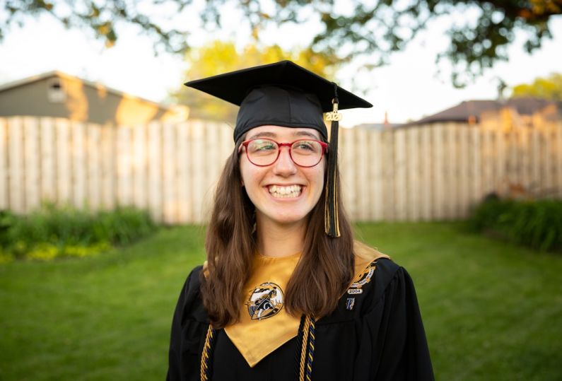 Empowering Communities - smiling woman in academic dress wearing academic hat