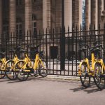 Sharing Economy - yellow bicycles beside black fence