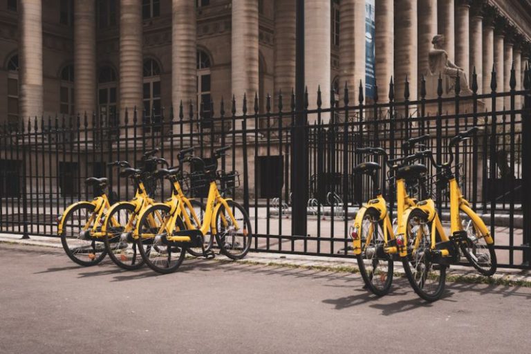 Sharing Economy - yellow bicycles beside black fence
