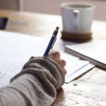 Mentorship Career - person writing on brown wooden table near white ceramic mug