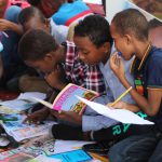 Continuous Learning - boy in blue and white plaid shirt reading book