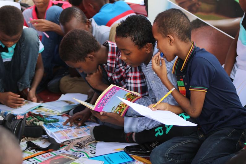 Continuous Learning - boy in blue and white plaid shirt reading book