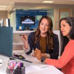 Collaboration Power - two women sitting at a table looking at a computer screen