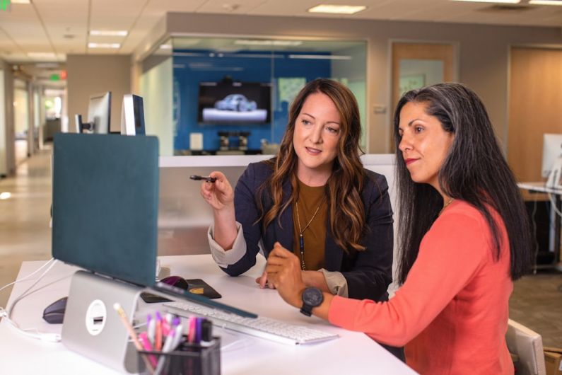 Collaboration Power - two women sitting at a table looking at a computer screen