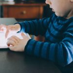 Technology Role - boy sitting on chair beside table using tablet computer