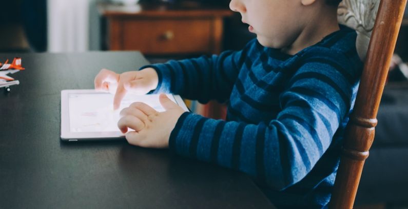 Technology Role - boy sitting on chair beside table using tablet computer