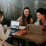 Work Culture - three people sitting in front of table laughing together