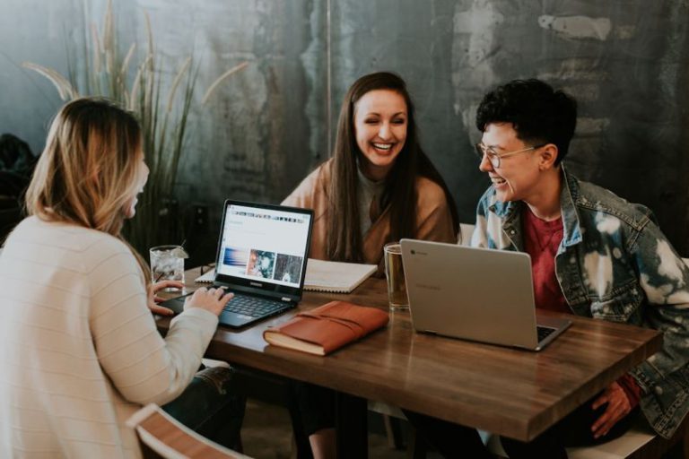 Work Culture - three people sitting in front of table laughing together